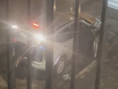 Un VUS blanc dont la porte passager et le coffre sont ouverts. La vue est g&ecirc;n&eacute;e par les barreaux d&rsquo;un balcon.