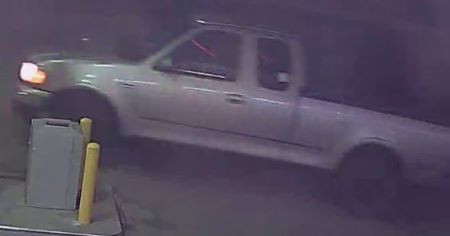 A front image of an older model, light-coloured pick up truck. 