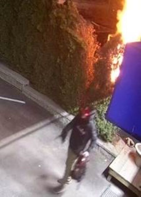 Photo du suspect s&rsquo;&eacute;loignant d&rsquo;une haie en feu, un sac &agrave; dos dans la main. 