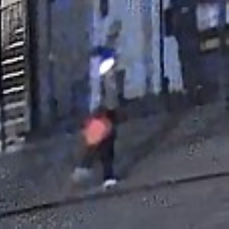 A colour image of a person in a jacket with the hood up, carrying a red gas can in their hand. 