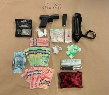 An image of package drugs, cash, and weapons including a pistol and knife are displayed on a table as evidence with 24-368 CFSEU-BC  written on the evidence paper underneath them.