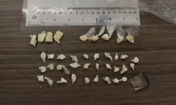 Individually wrapped suspected drugs of various sizes laid out on a table after being seized by Police