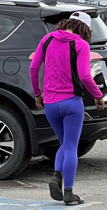 Photo pleine longueur de la suspecte qui s&rsquo;&eacute;loigne en marchant dans un terrain de stationnement.