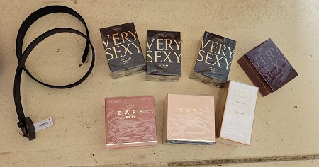 Des biens vol&eacute;s, dont une ceinture noire et sept bo&icirc;tes de parfum, sur un plancher carrel&eacute;.