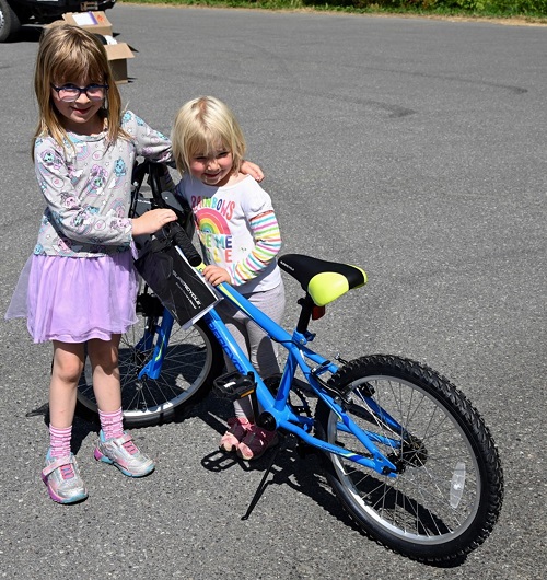 Winners of the bike raffle (Kaitlyn Almas and sister Allison Mack) standing with new bike