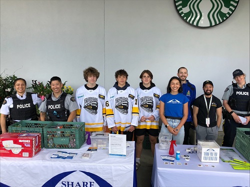 Group photo of Coquitlam RCMP Officers, staff, SHARE Society and Coquitlam Express hockey players