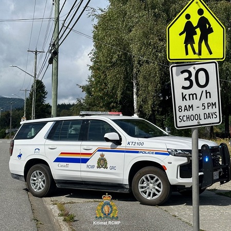photo of a police car parked behind a school zone sing