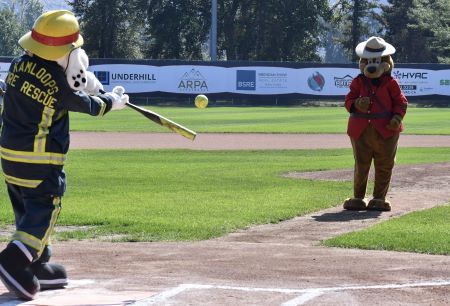 Sparky, la mascotte du service d&rsquo;incendie et de sauvetage de Kamloops (un dalmatien portant un uniforme de pompier), prend son &eacute;lan pour frapper une balle molle lanc&eacute;e par le sergent Ours prudent, la mascotte de la GRC de Kamloops (un ours portant une tunique rouge et un chapeau de la GRC). 