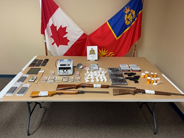 A photo  if seized various drugs and weapons. Items are placed on a table with two flags in the back