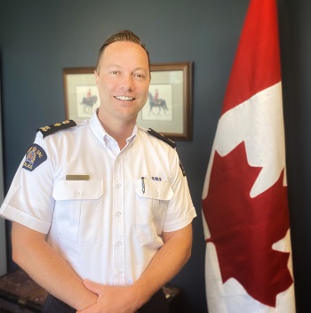 Superintendent Todd Preston standing next to a Canada flag