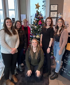 Photo of six Victim Services staff members and volunteers standing around a Christmas tree at a community event. 