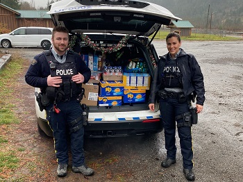 Two police officers stand behind an open police car filled with donations