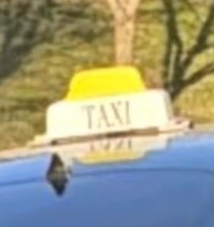 Un gros plan d&rsquo;une enseigne de taxi jaune et blanche sur le toit d&rsquo;un v&eacute;hicule fonc&eacute;. 