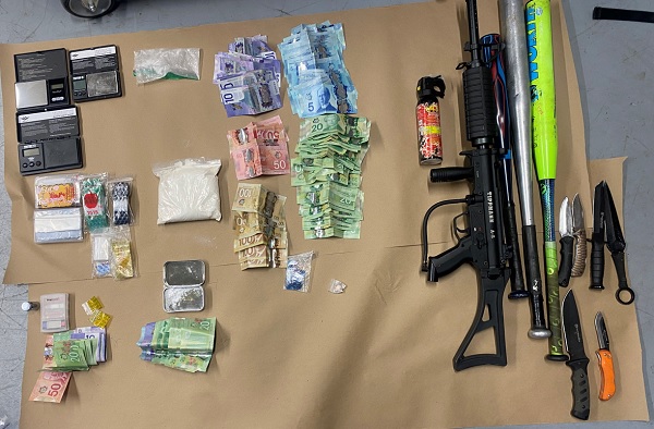 Seized items displayed: bats, knives, cash, drugs, scales