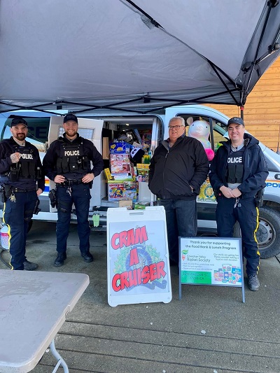 RCMP officers standing in front of a police prisoner wagon filled with toys