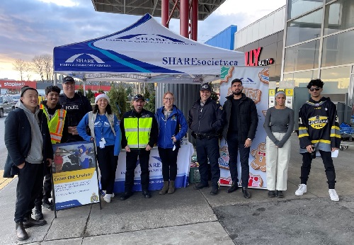 Group photo of Coquitlam RCMP Officers, staff, SHARE Society and Coquitlam Express hockey players at the Coquitlam Cram the Cruiser location.