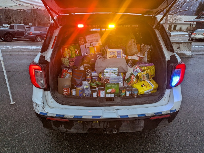 The rear truck of a RCMP vehicle filled with groceries and toys
