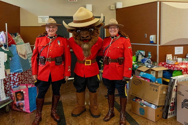 Two RCMP officers in red serge with RCMP mascot Sgt. Bison.