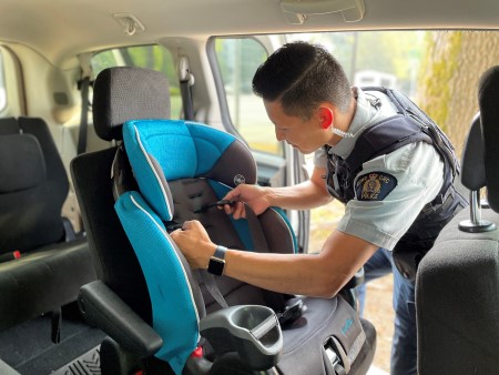 Vue de l&rsquo;int&eacute;rieur d&rsquo;un agent de police en uniforme qui v&eacute;rifie un si&egrave;ge pour enfant dans un v&eacute;hicule