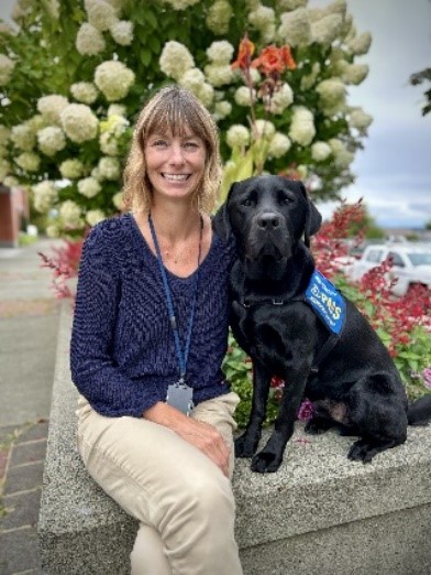 Milo the support dog sitting next to victim services worker Tamara Coco