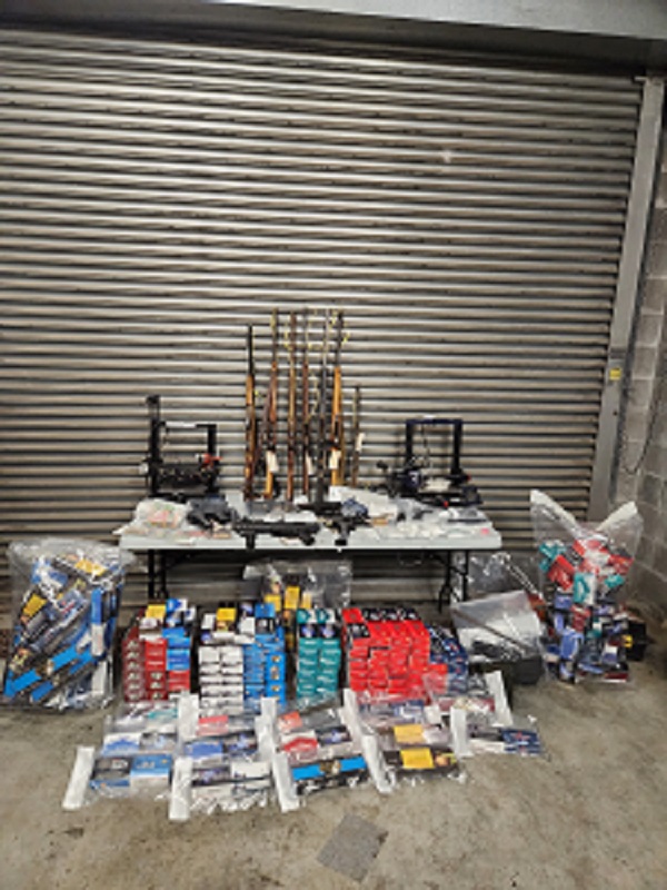 Photo of seized items including guns, drugs, cigarettes and money.