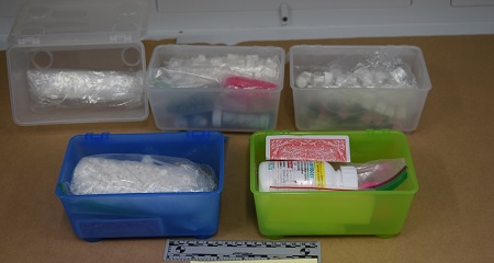 Various illicit drugs in five plastic bins.