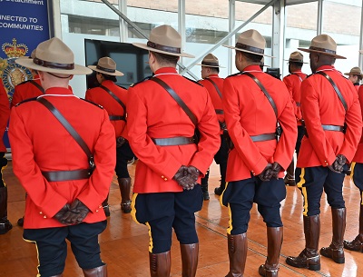 A photo of the backs several RCMP members wearing Red Serge indoors
