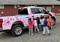 Children putting pink hand prints on police truck