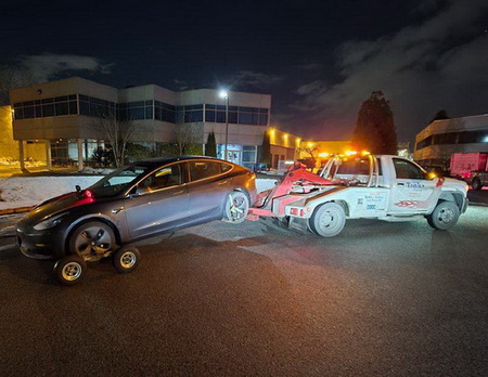 Grey vehicle being towed by a two truck