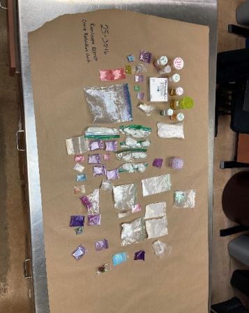 Des drogues pr&eacute;sum&eacute;es de diverses couleurs dans des sachets et des flacons de pilules sont &eacute;tal&eacute;es sur une table.