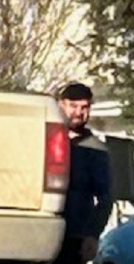 Close up of man standing beside white Dodge Ram