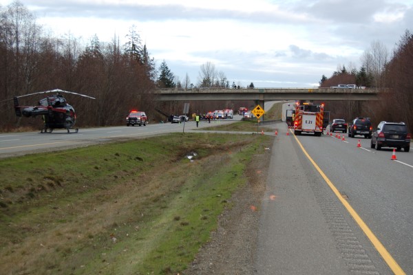BC Highway Patrol, firefighters, and an air ambulance in the aftermath of a head-on collision involving a white Chevrolet pickup and a grey Toyota Prius on Highway #19 near the Church Road overpass