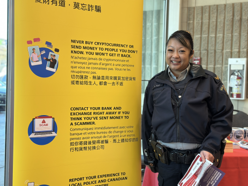 Richmond RCMP Officer standing beside a banner