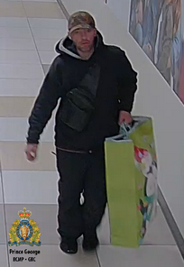 Photo of the suspect wearing dark clothing and a baseball hat and carrying a large yellow bag.