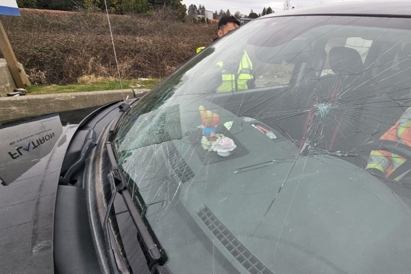 A BC Highway Patrol officer examines damage to a pilot vehicle after an overpass strike on Highway #99