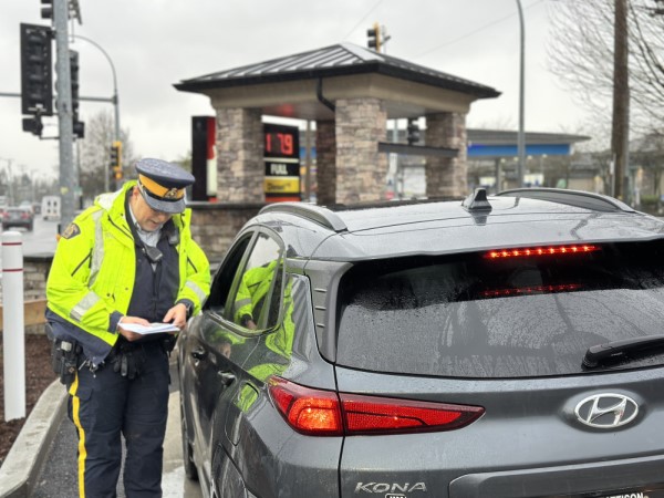 A BC Highway Patrol officer writes a distracted driving ticket in Richmond, BC