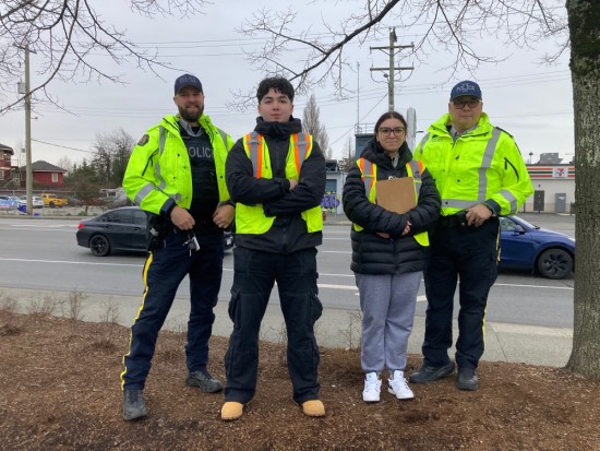 Richmond RCMP officers and volunteers standing at the side of the road and smiling