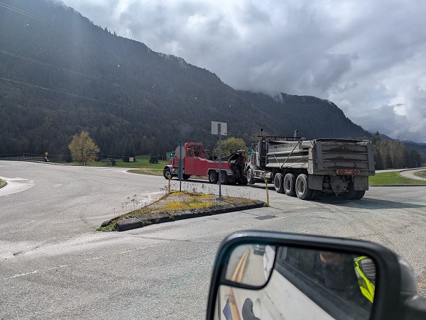 The fully-loaded dump truck being towed by a heavy-duty tow truck at the owner&rsquo;s expense