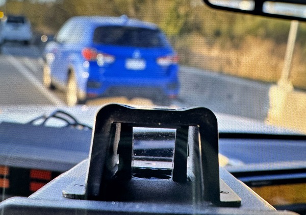 A laser reader shows 157 km/h as a blue car sits stopped in front of a BC Highway Patrol vehicle