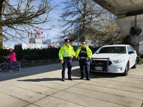 Photo of Richmond RCMP officer in a high visibility jacket and two cyclists on the sidewalk