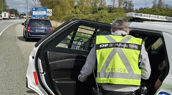A BC Highway Patrol officer stops a blue minivan with a forged Temporary Operating Permit on Highway #99