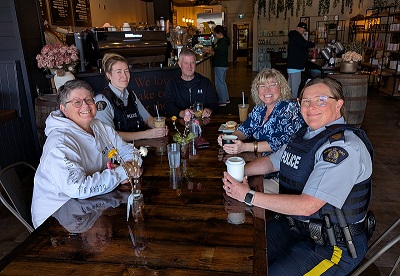 Photo of two Fort St John RCMP members sitting with three community members over a coffee