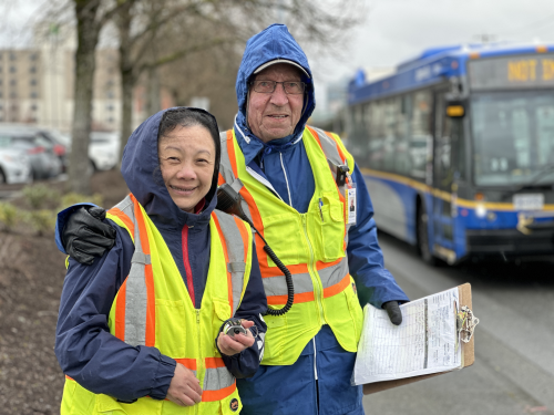 Two volunteers in rain jackets standing together smiling