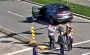 Five persons standing in crosswalk with a vehicle parked nearby
