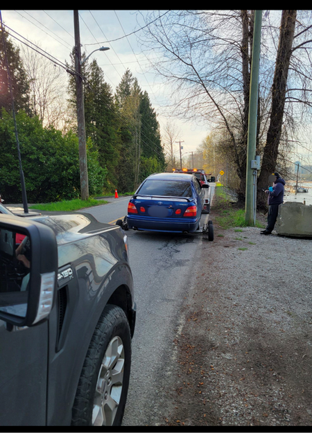 blue Toyota loaded onto flat bed tow truck at the side of the road