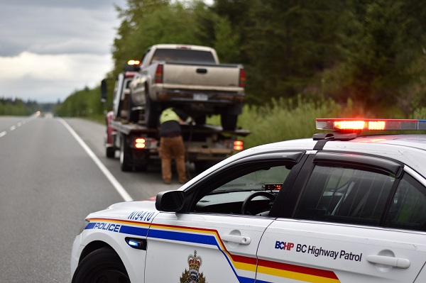 A BC Highway Patrol vehicle stopped in front of a tow truck as a pickup is impounded for excessive speed