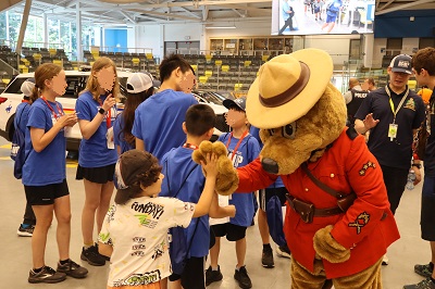Safety Bear gives a child a high five while surrounded by lots of people at a Coquitlam RCMP event.