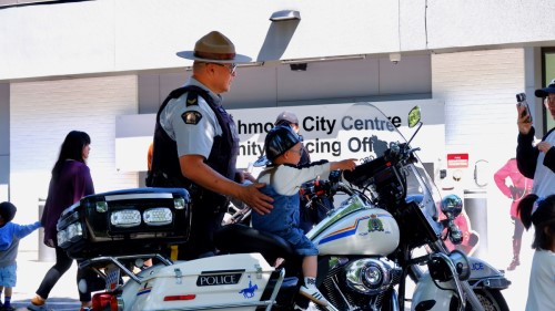 A RCMP officer from Richmond standing next to a child on a motorcycle