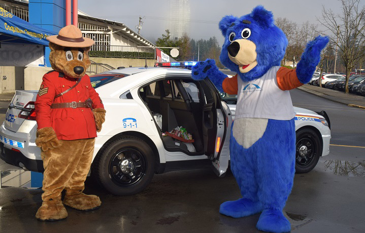 RCMP Safety Bear with the Share Society Bear standing in front of a marked RCMP vehicle