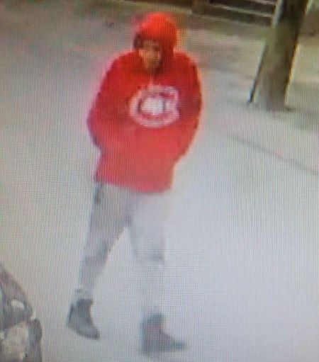 Le suspect qui porte un chandail &agrave; capuchon rouge avec un logo sur le devant et des chaussures fonc&eacute;es.